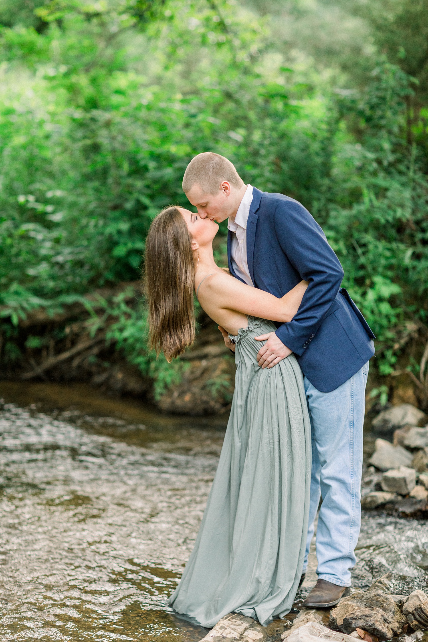 groom kisses bride dipping her backwards over creek
