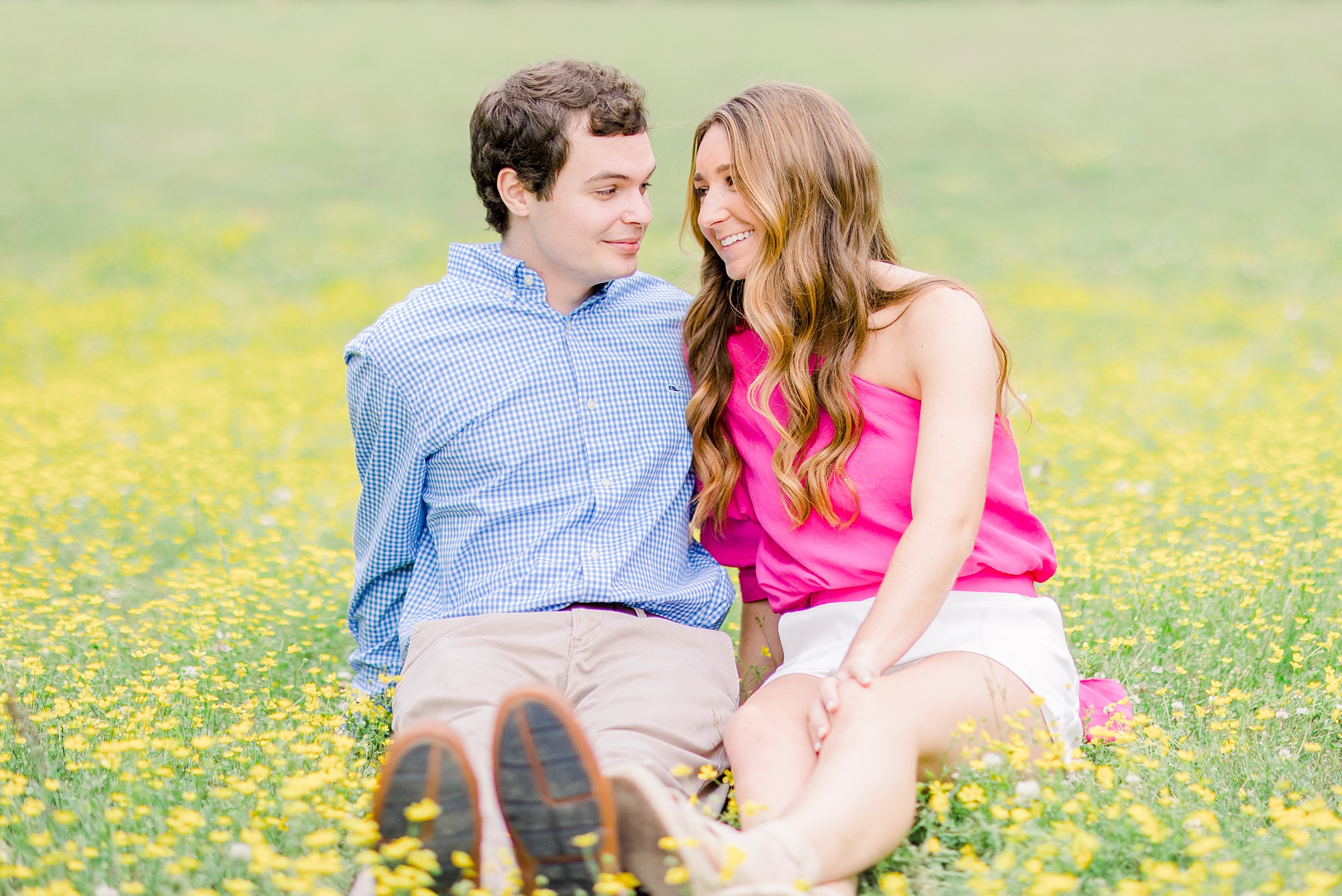 engaged couple sits together in field with yellow flowers