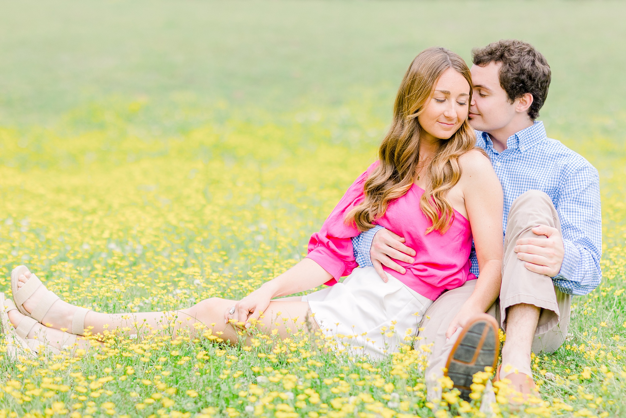 groom nuzzles bride's cheek during spring engagement photos in field