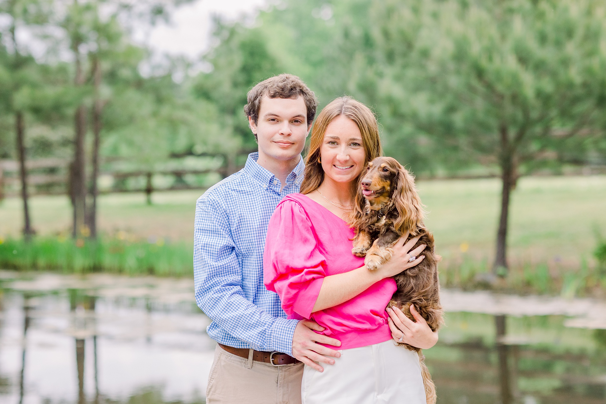 bride and groom hold puppy on dock during spring Birmingham Alabama Engagement Sessions