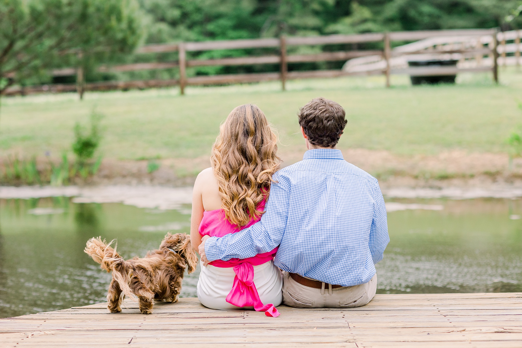 couple sits looking at water on dock with dog