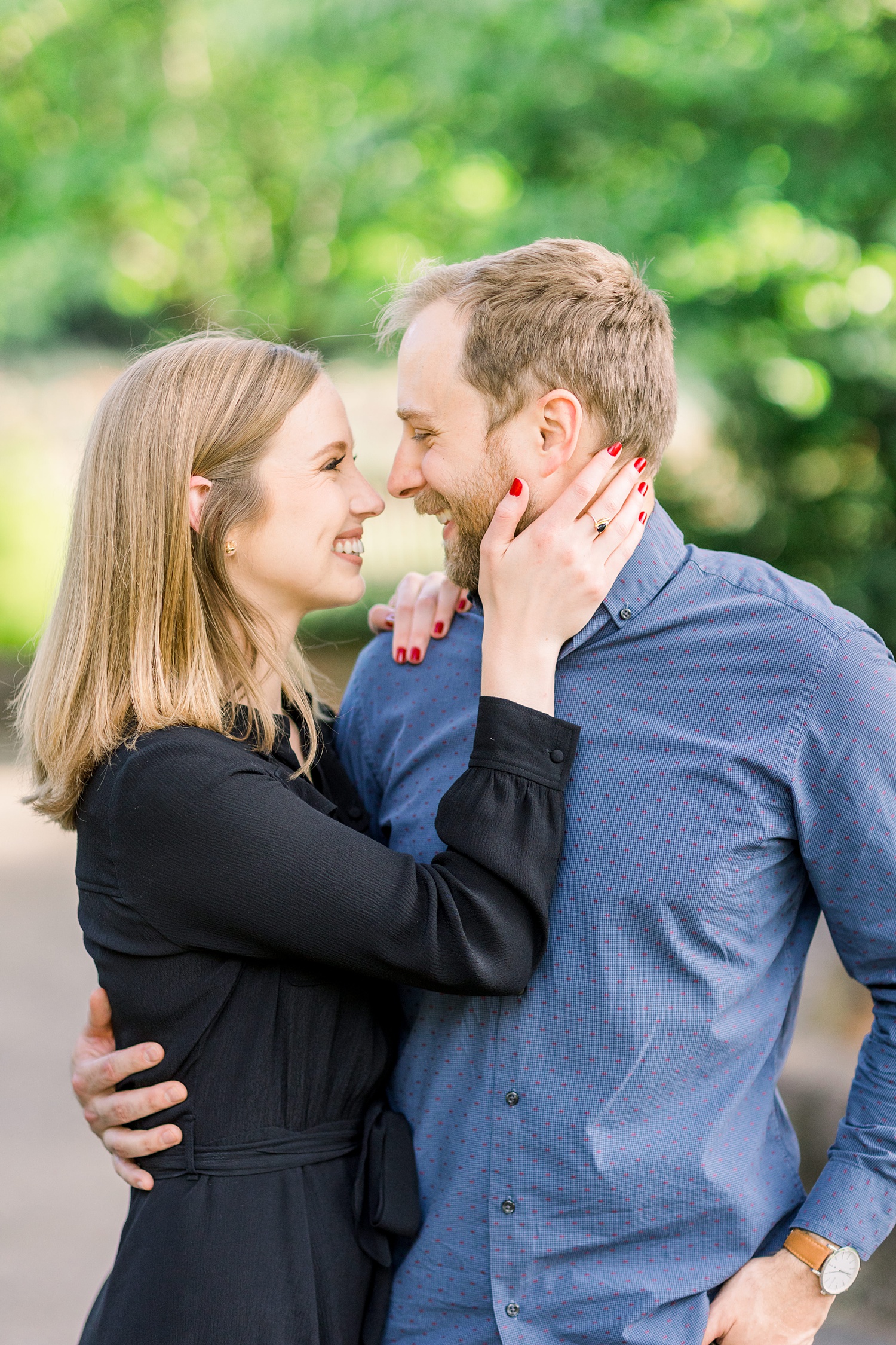 bride holds groom's chin during engagement photos at Birmingham Botanical Gardens