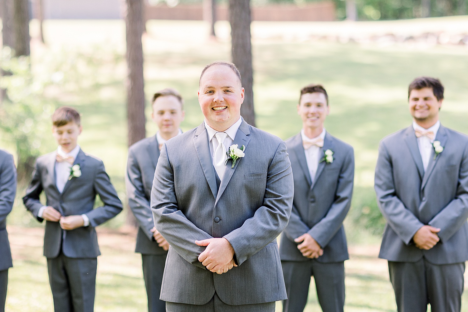 groom poses with groomsmen in grey suits before Douglas Manor wedding