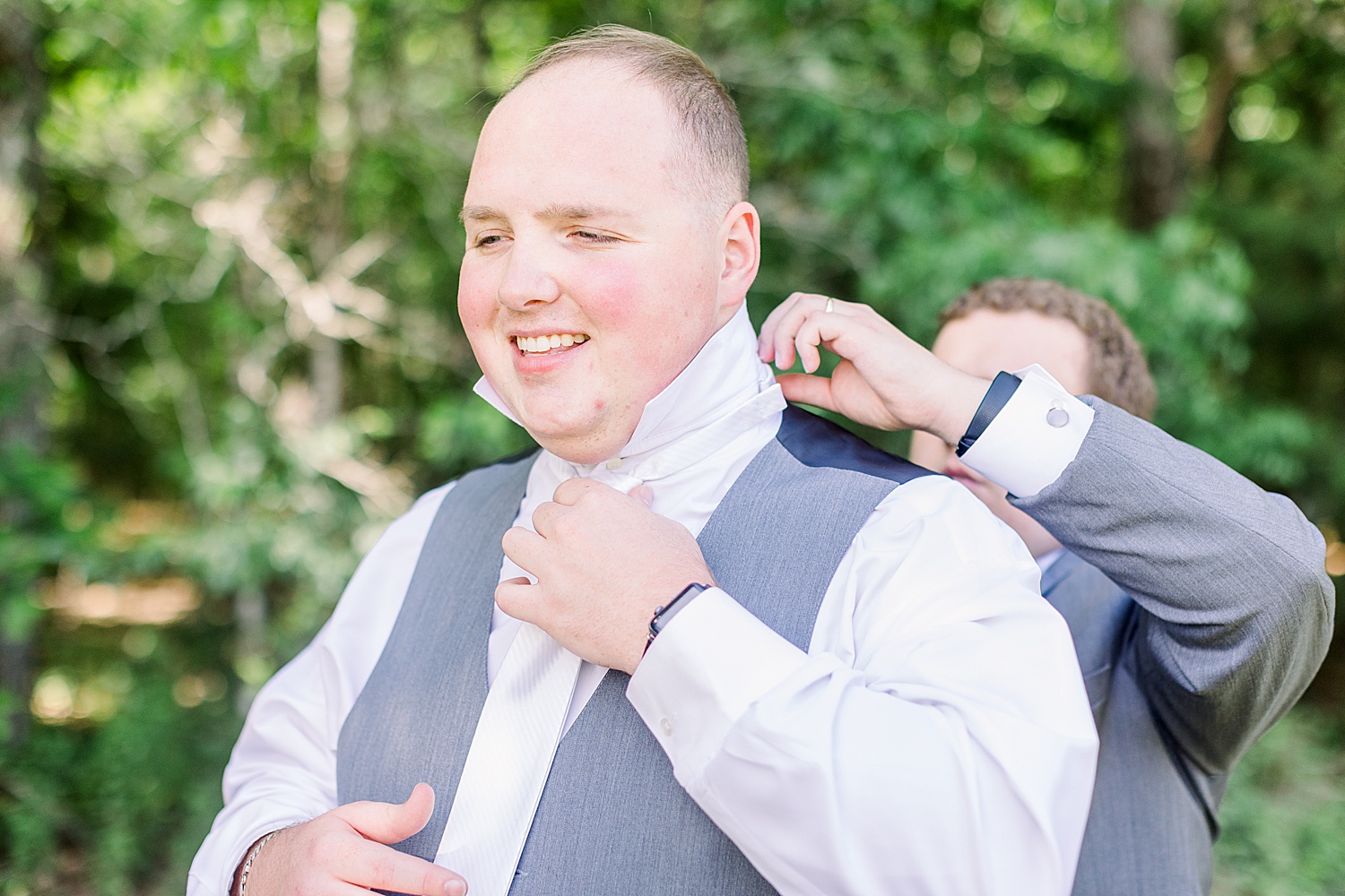 groomsman adjusts collar for groom