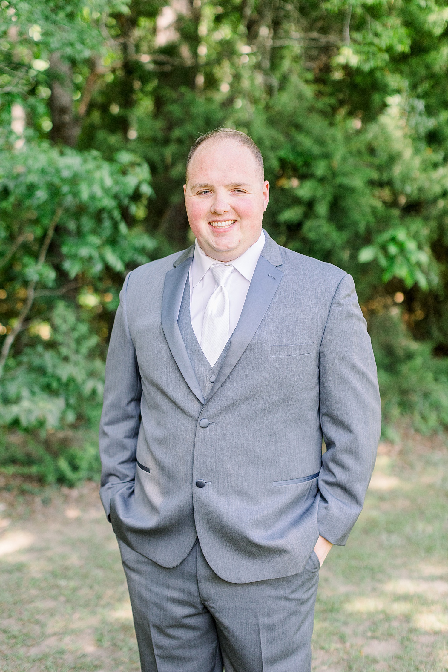 groom poses with hands in his pockets