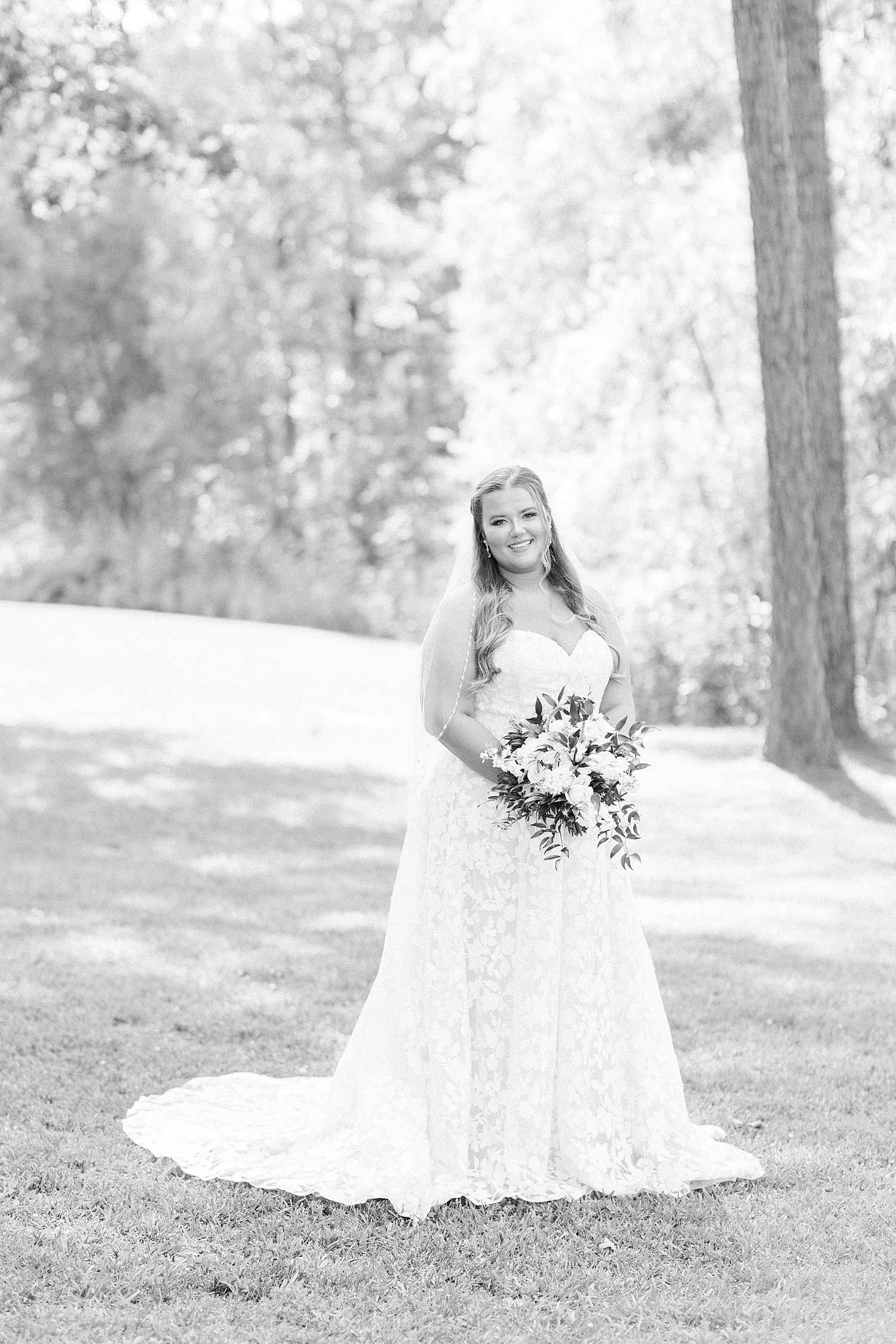 bride holds bouquet standing in trees at Douglas Manor