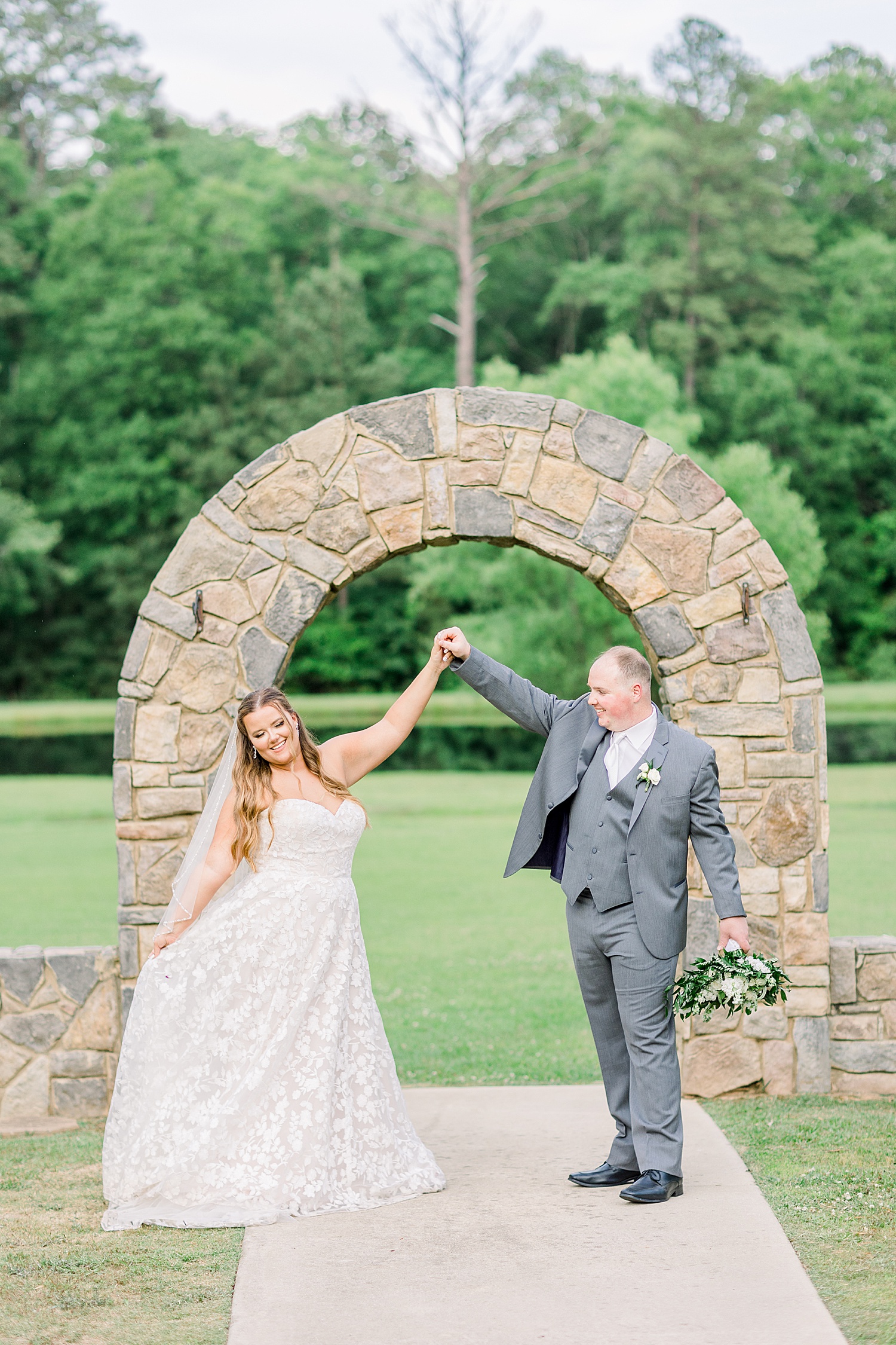 bride and groom twirl under stone arch at Douglas Manor