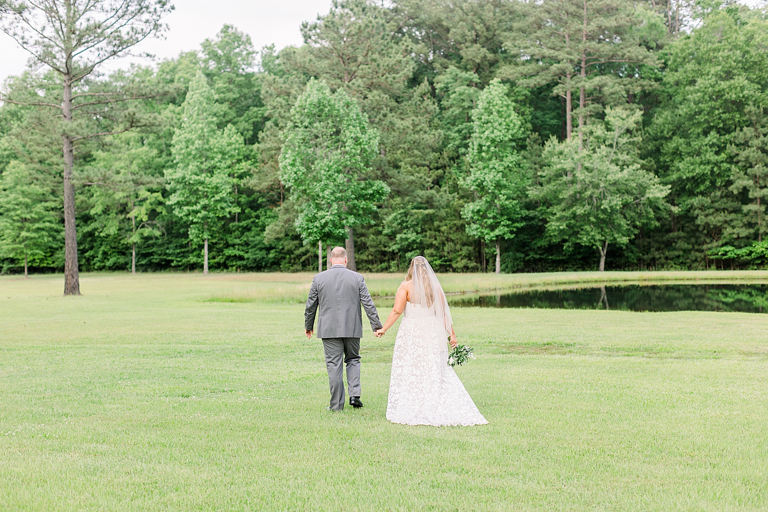 newlyweds walk through field at Douglas Manor