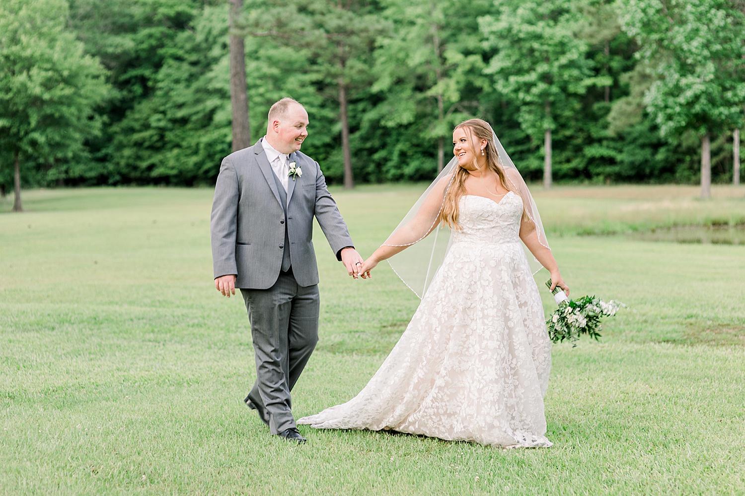 bride and groom walk through field at Douglas Manor