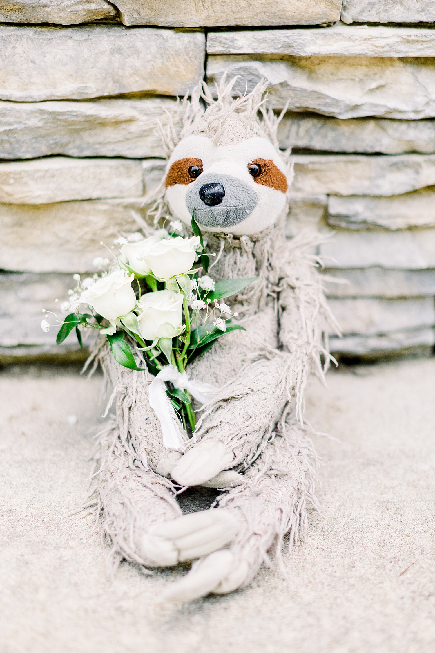sloth holds ivory flowers before AL wedding
