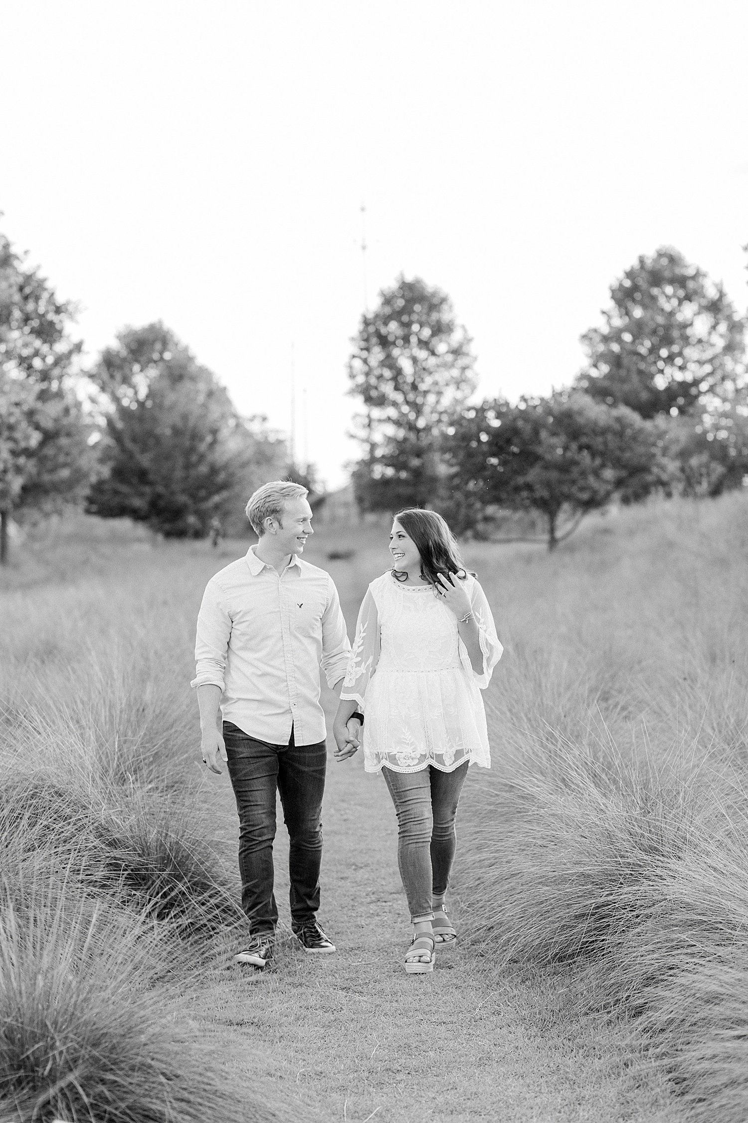 engaged couple walks through field at Railroad Park