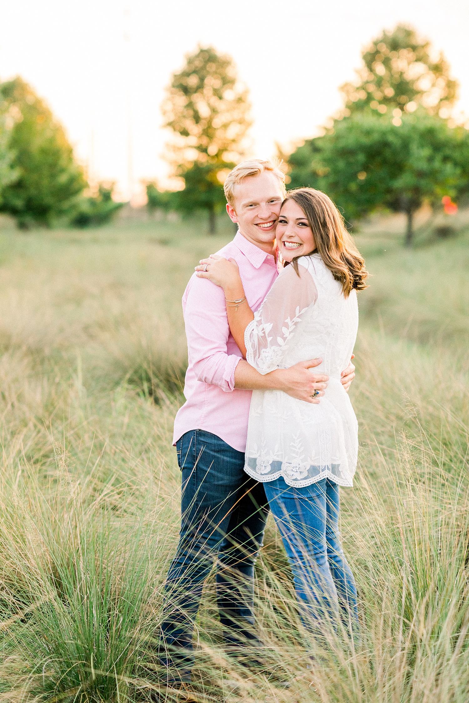 groom hugs bride in field during Railroad Park engagement session