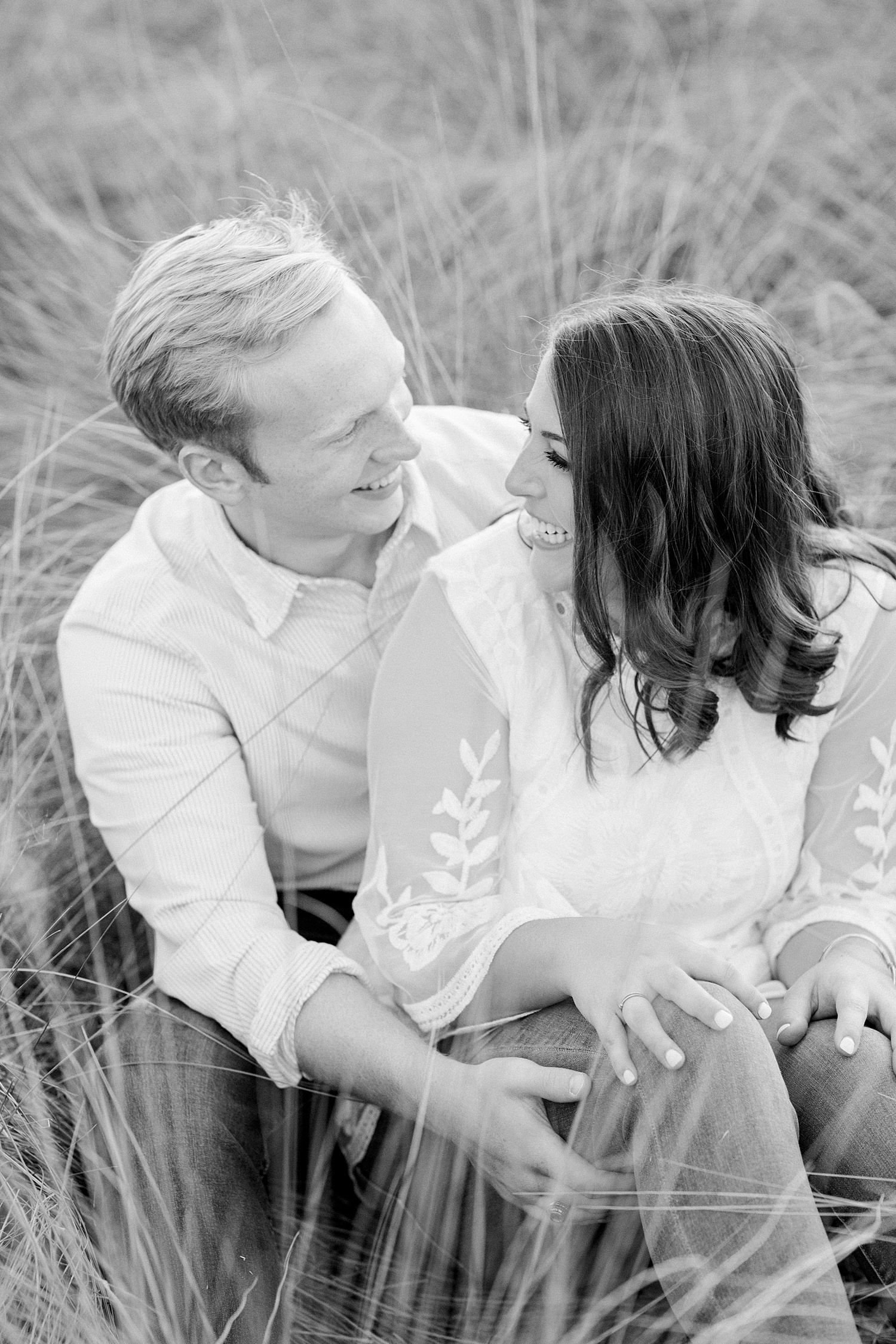 bride and groom laugh together sitting in field during Downtown Birmingham engagement session