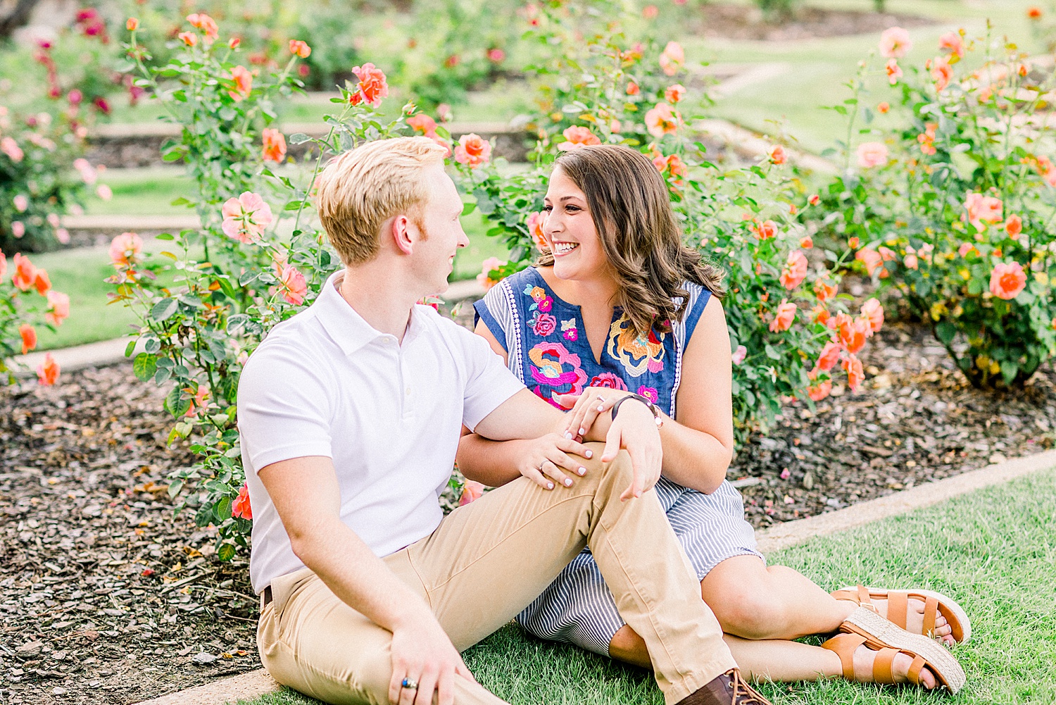 engaged couple sits by bed of flowers in Birmingham Botanical Gardens
