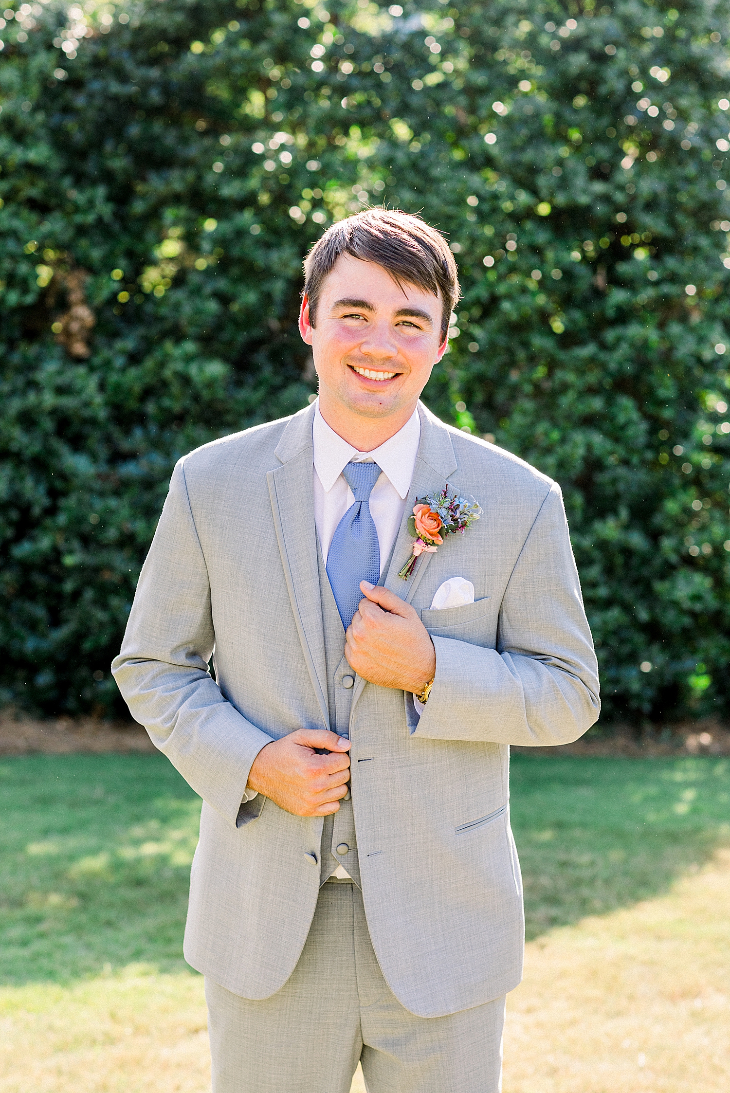 groom in grey suit holds lapel