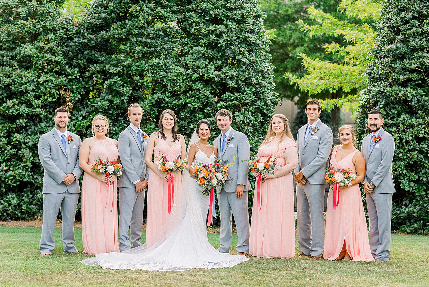 bride and groom pose with bridal party in grey and pink