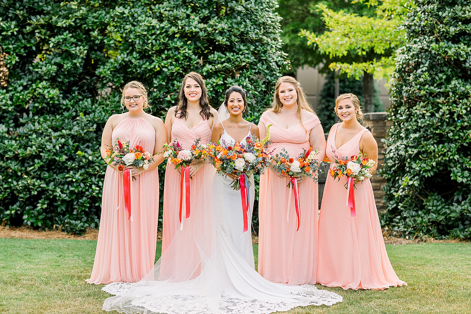 bride poses with bridesmaids in pink dresses