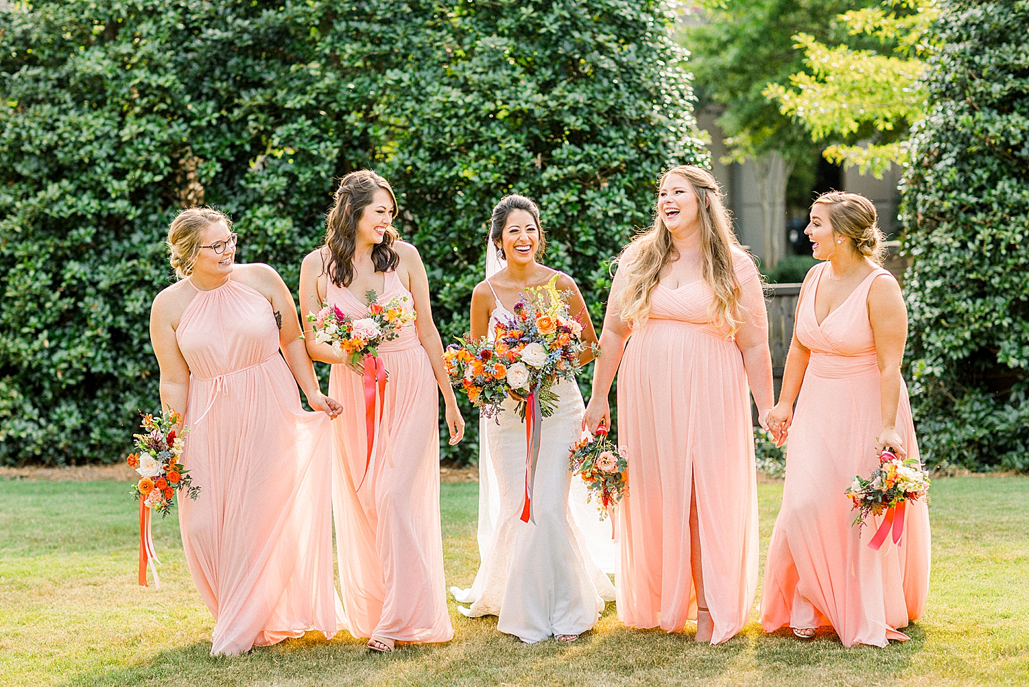 bride laughs with bridesmaids in pink dresses