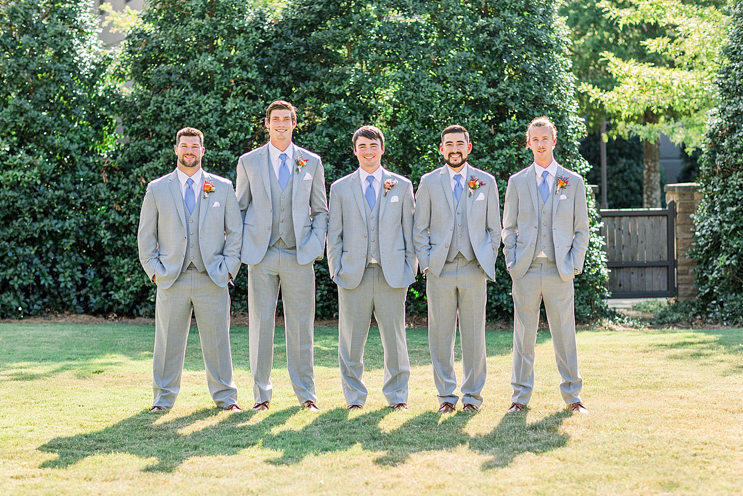 groom poses with groomsmen in grey suits