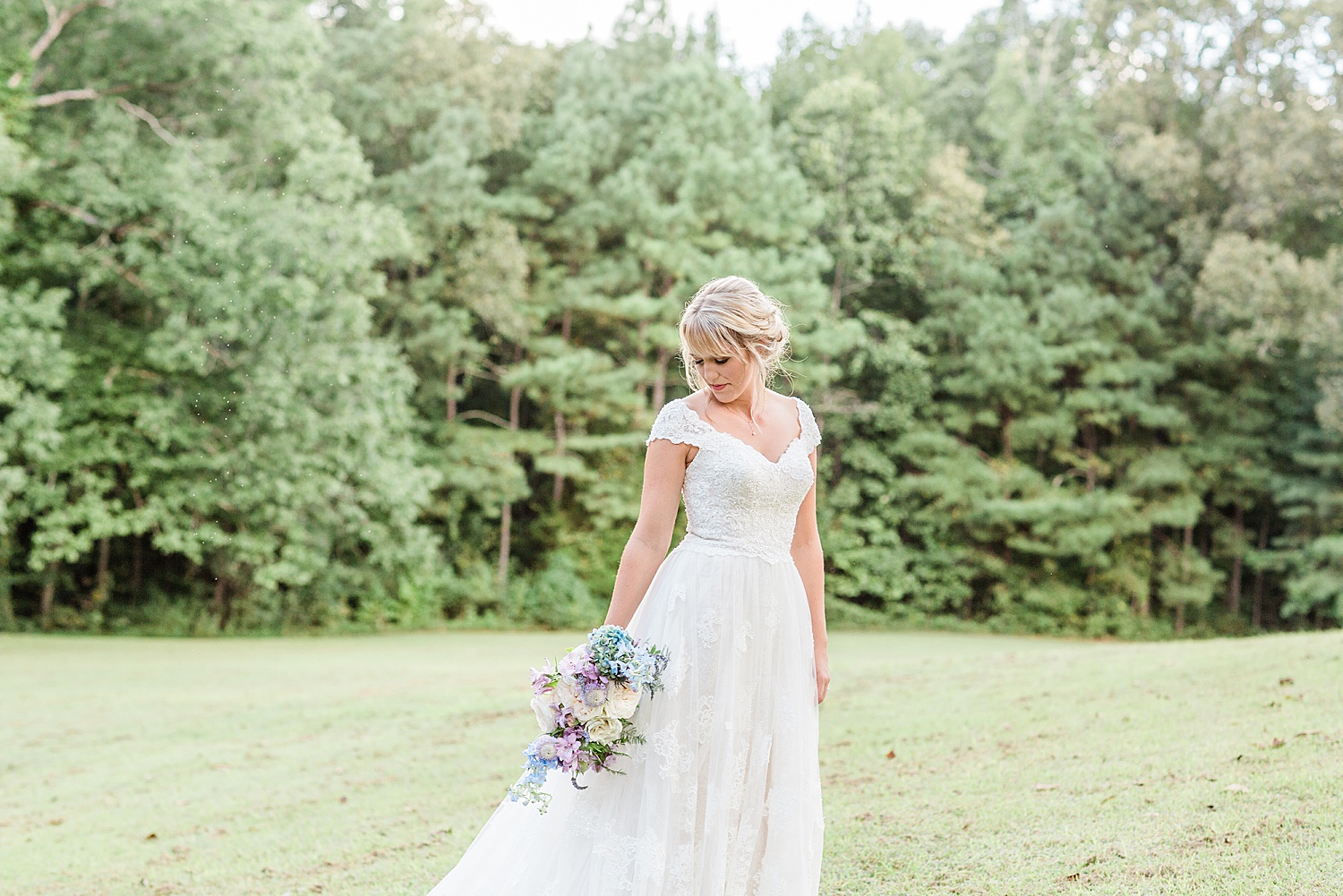 bride holding bouquet in open field before wedding