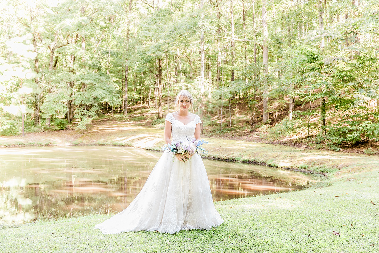 Bride holding wedding bouquet near pond in Alabama