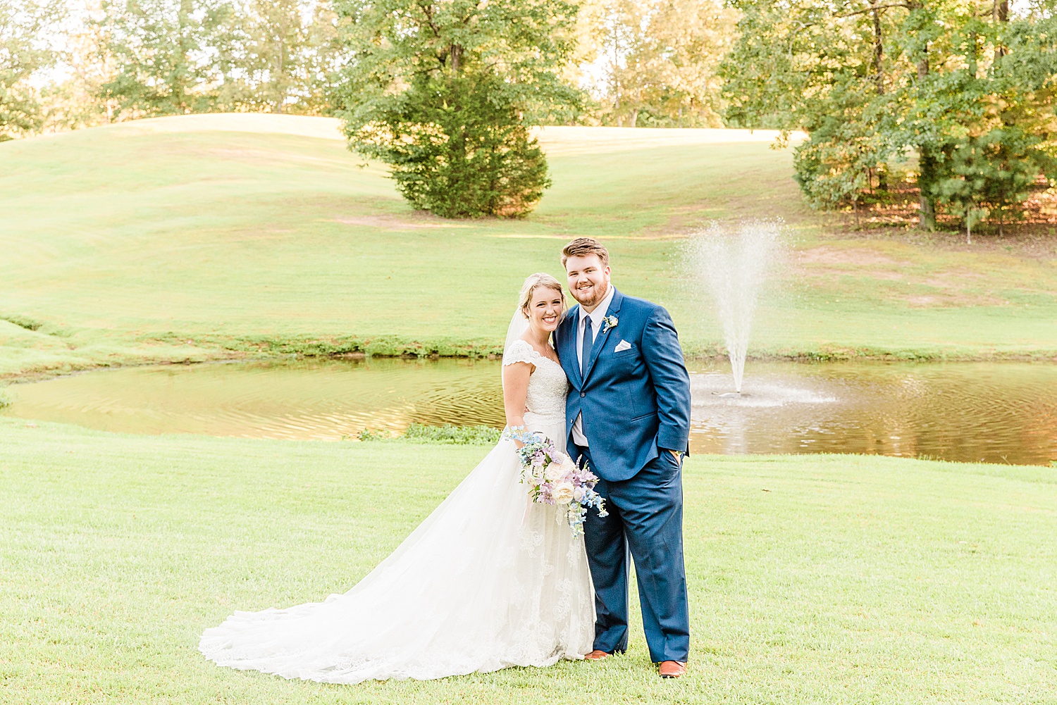 bride and groom stand by pond on the grounds of applewood farms in AL