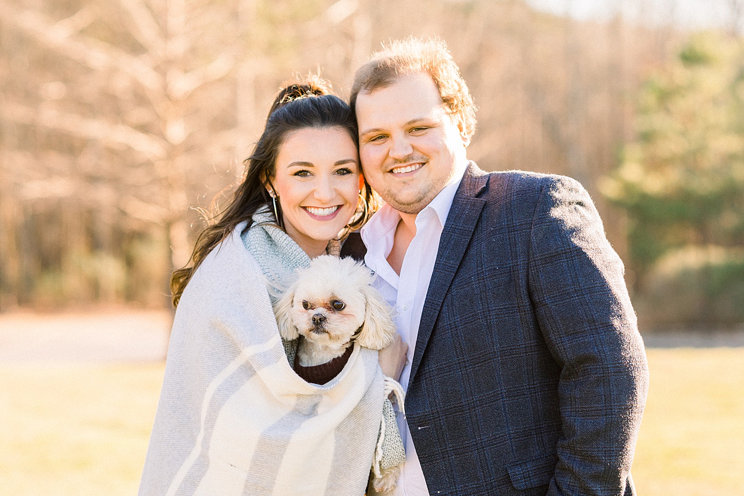 Engaged couple wrapped up in a blanket with their dog during Winter engagement session