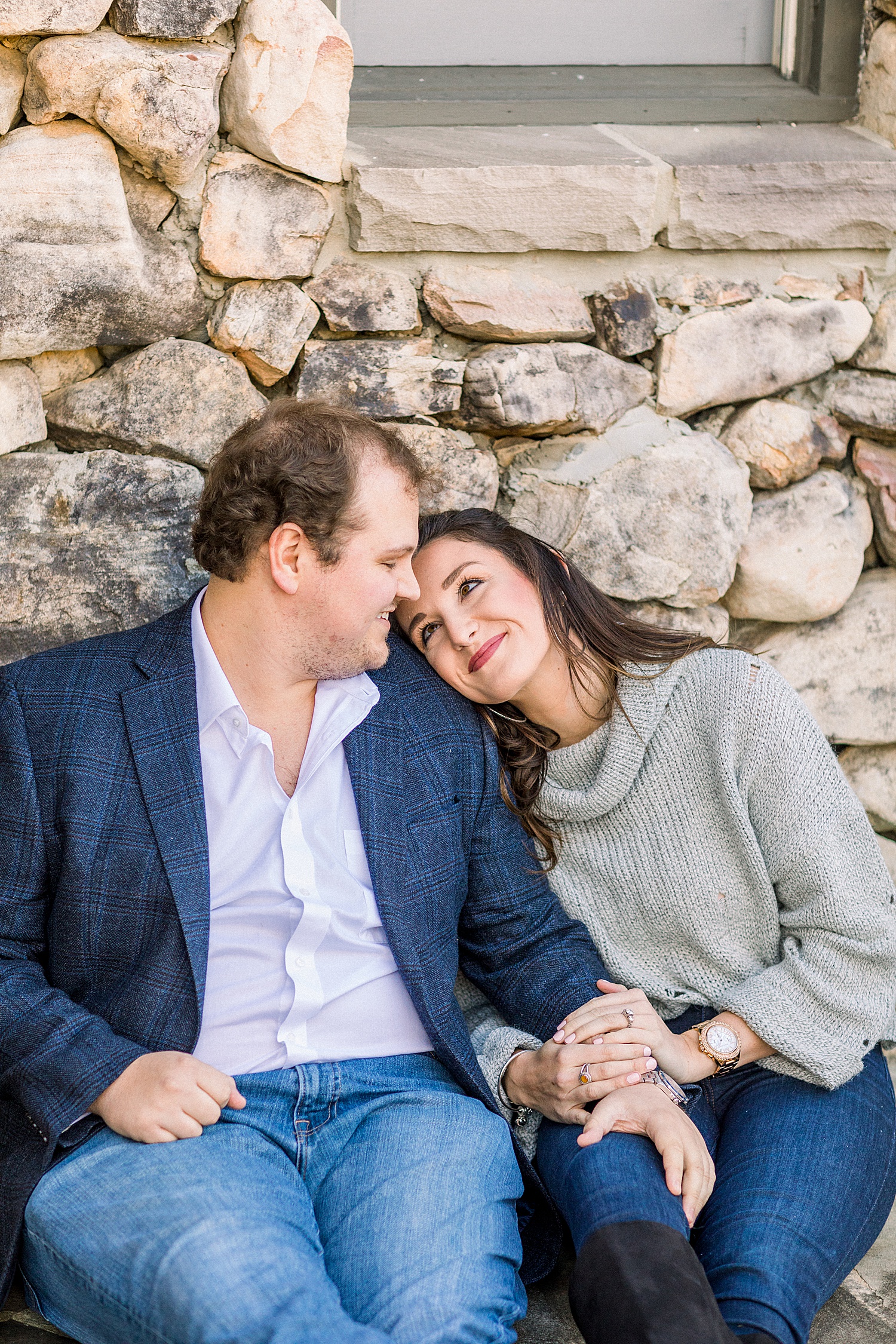 couple sit against stone wall in Mount Laurel in Birmingham AL for engagement session by Chelsea Morton Photography