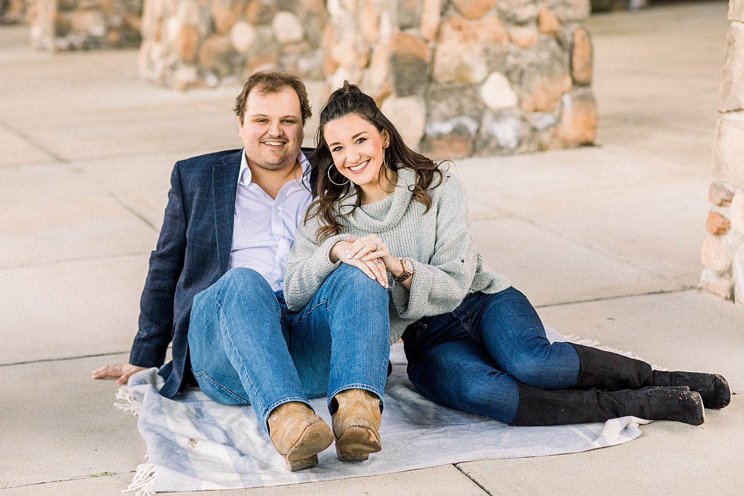 couple sits on blanket near stone walls during AL engagement session