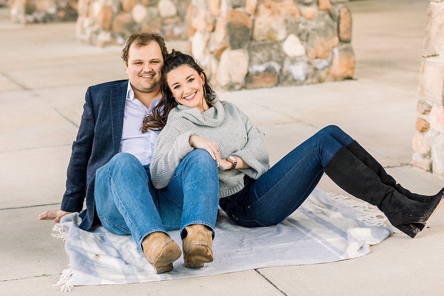 couple sits on blanket near stone walls during Birmingham AL engagement session