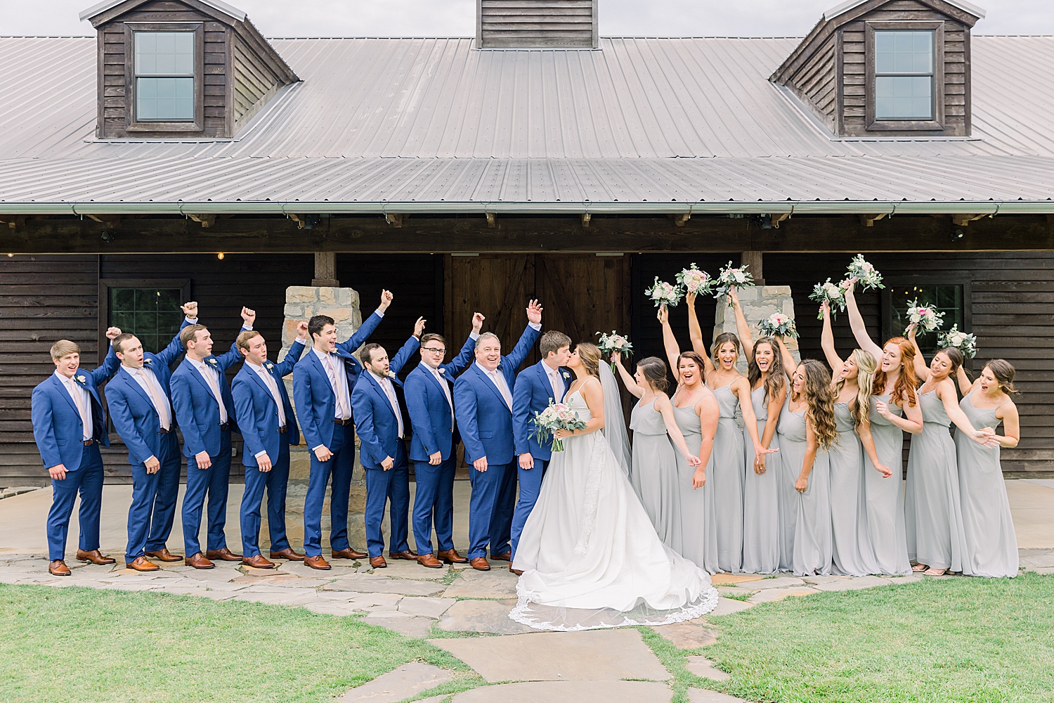 bride + groom kiss surrounded by bridal party during AL wedding at The Barn at Shady Lane captured by Chelsea Morton Photography