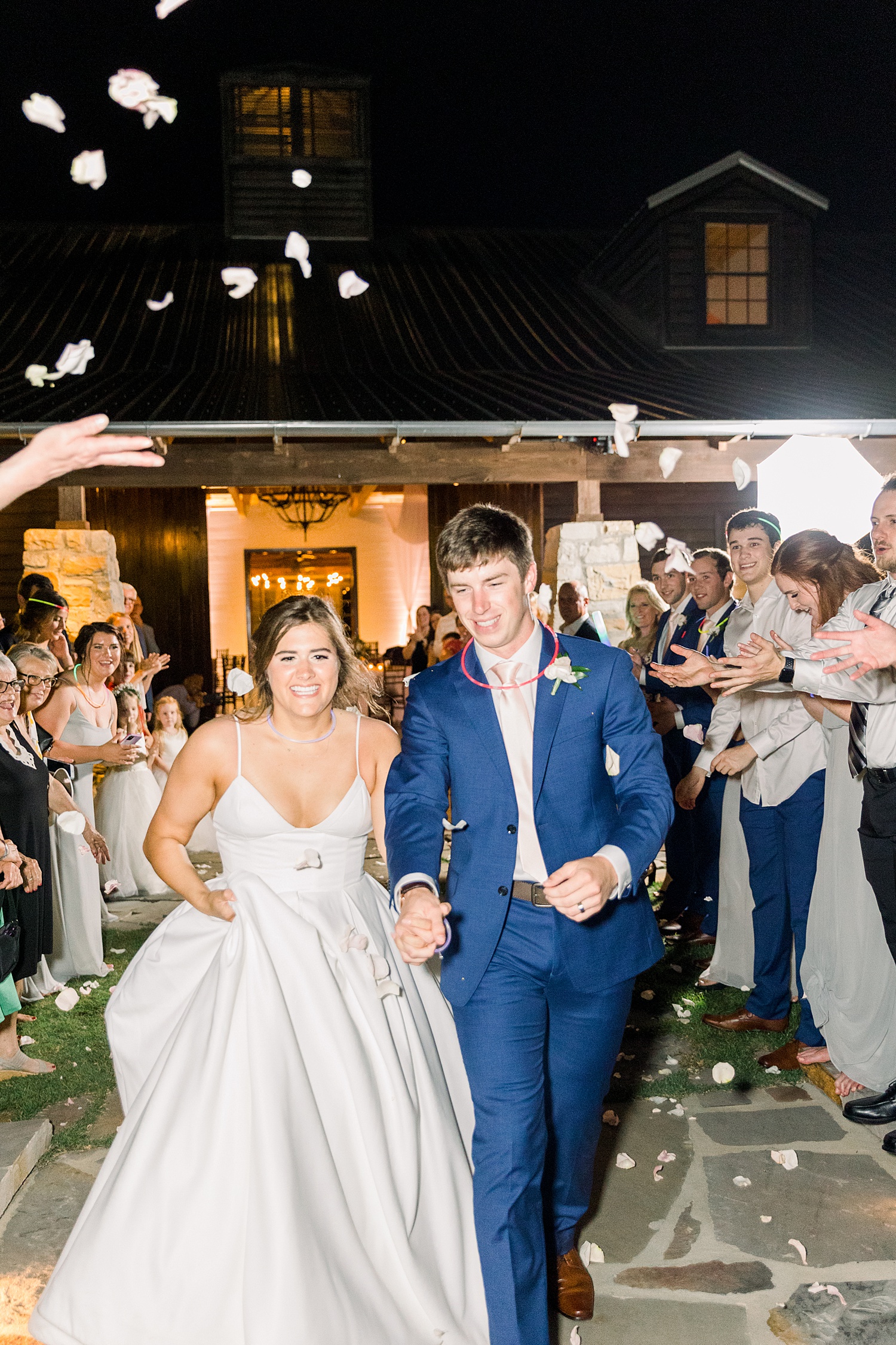 wedding guests throw flower pedals at newlyweds at the end of the night