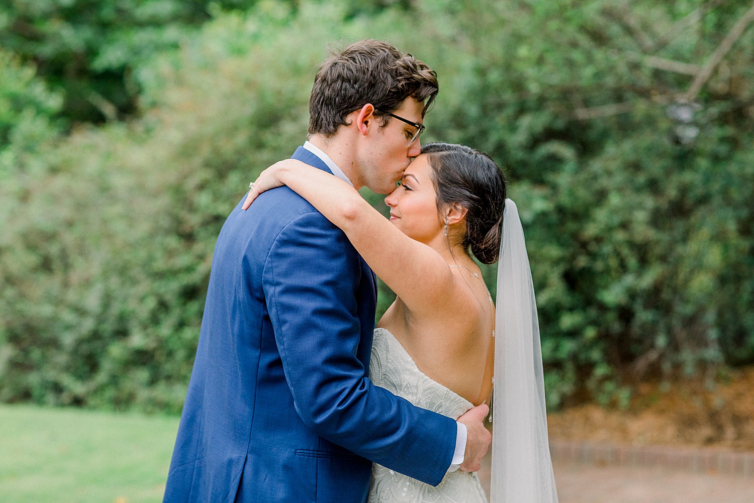 groom kisses brides head before AL wedding ceremony