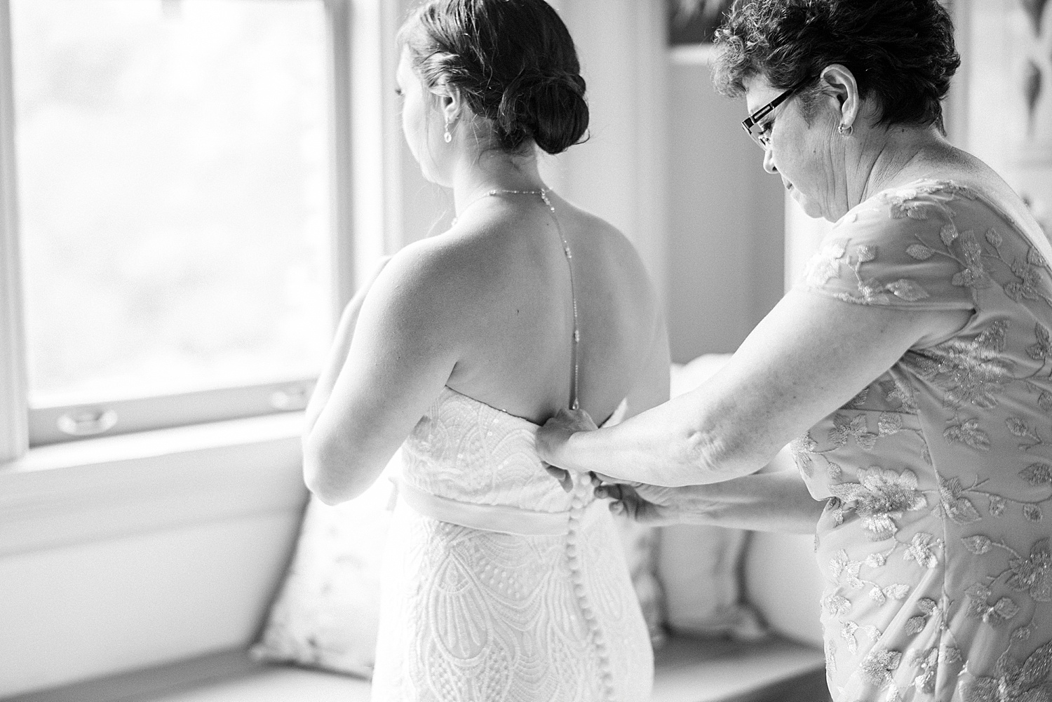 mom helping bride with wedding dress