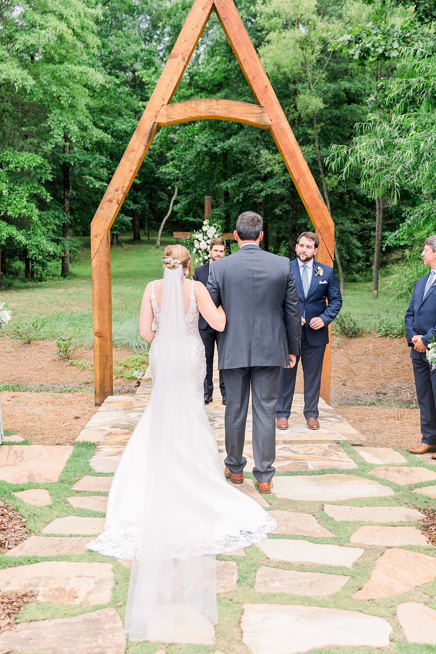 Father-of-the-bride and daughter walk down aisle in outdoor summer wedding ceremony