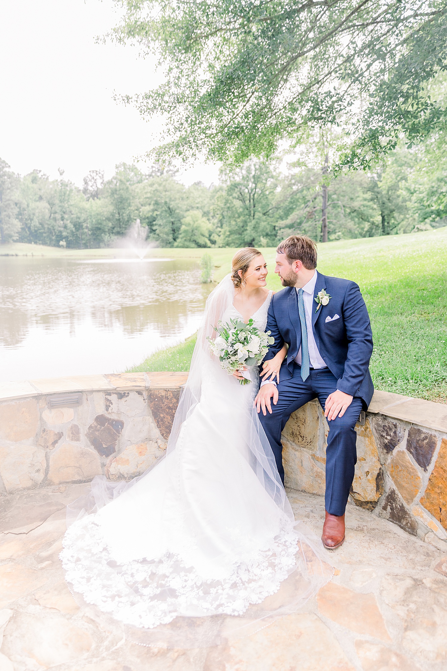 newlyweds share intimate moment sitting on decorative stone wall at Belle farms