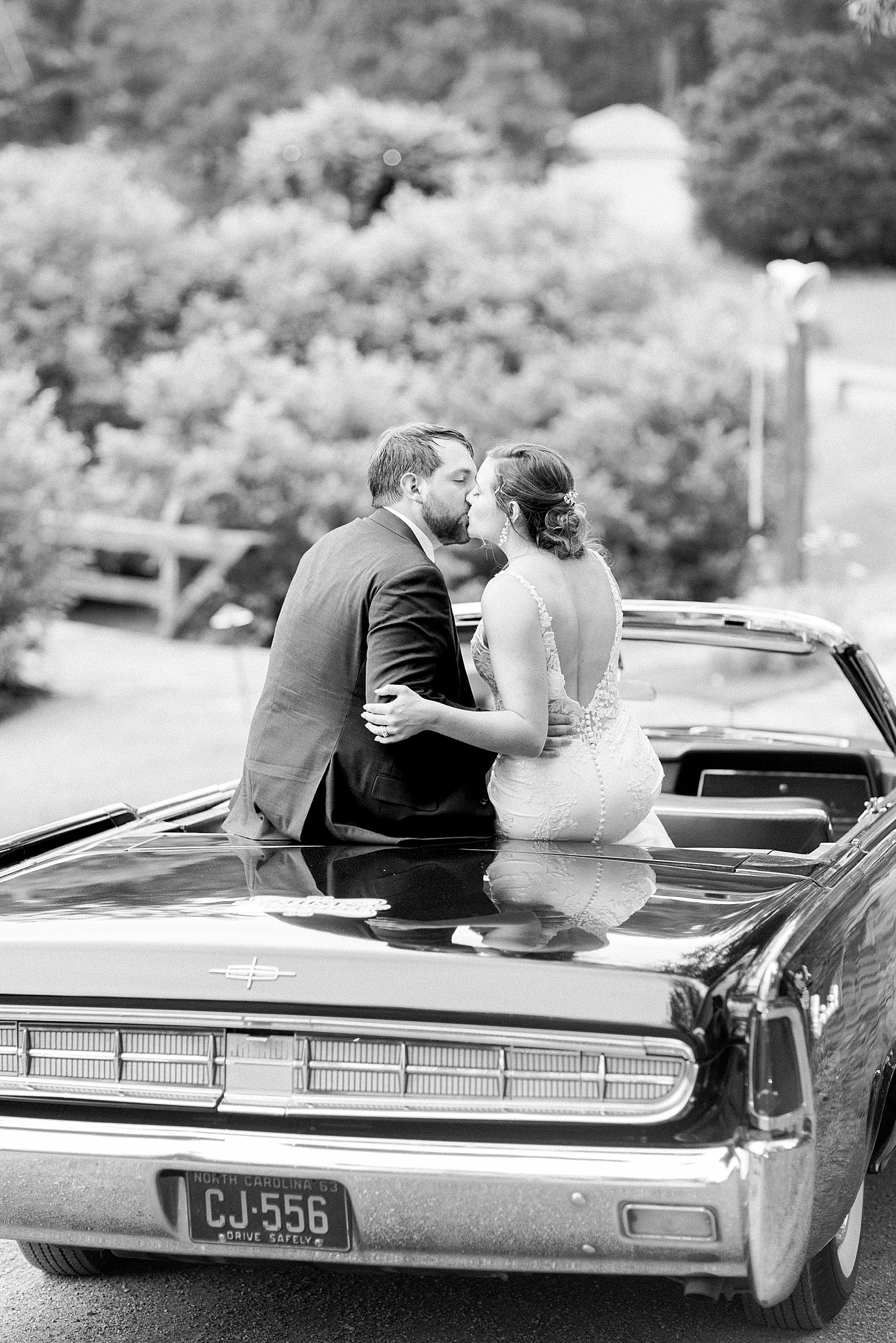 newlyweds sit on classic car from Coats Cars