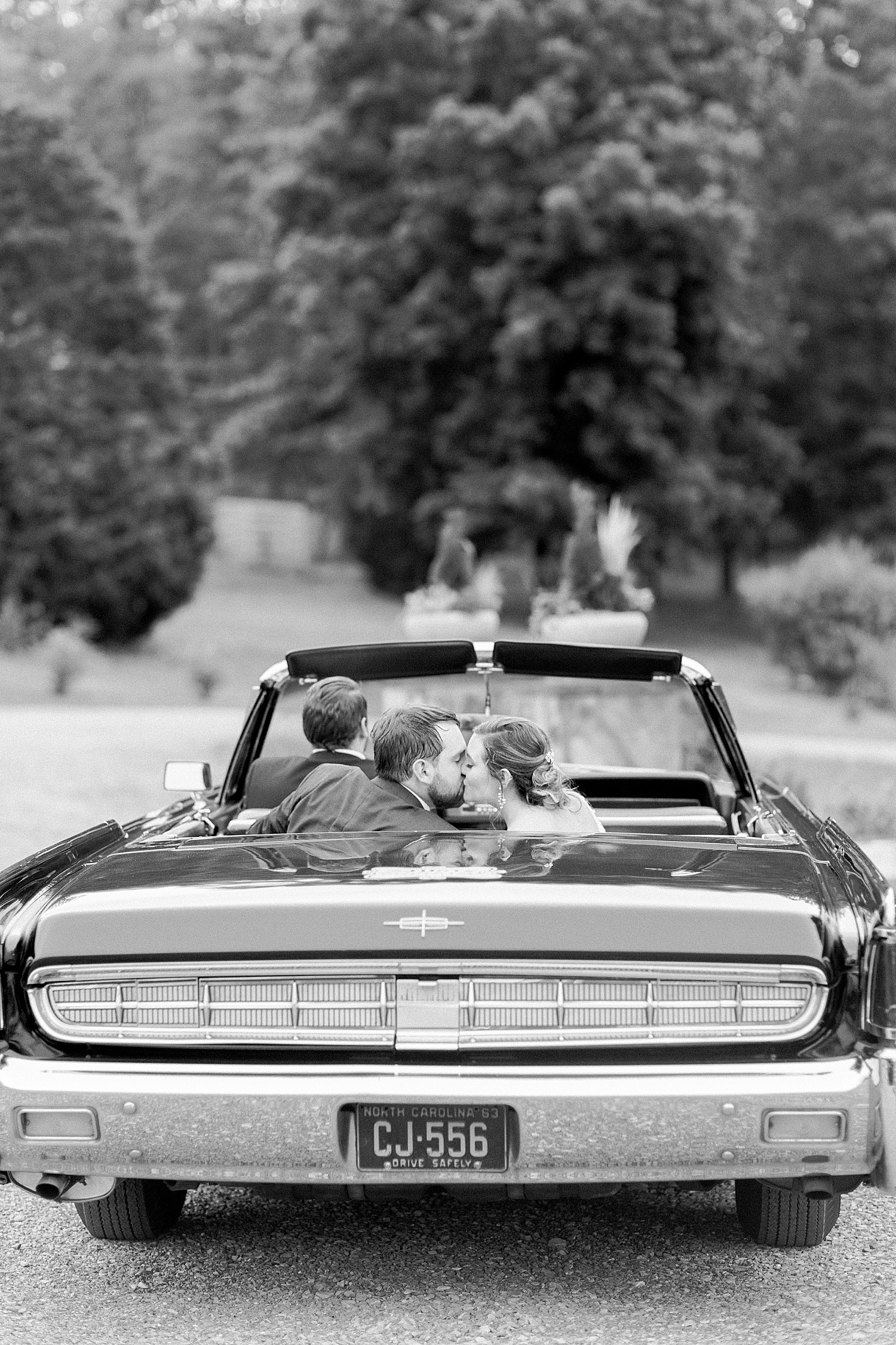newlyweds drive away in classic car at Belle Farms summer wedding in Alabama