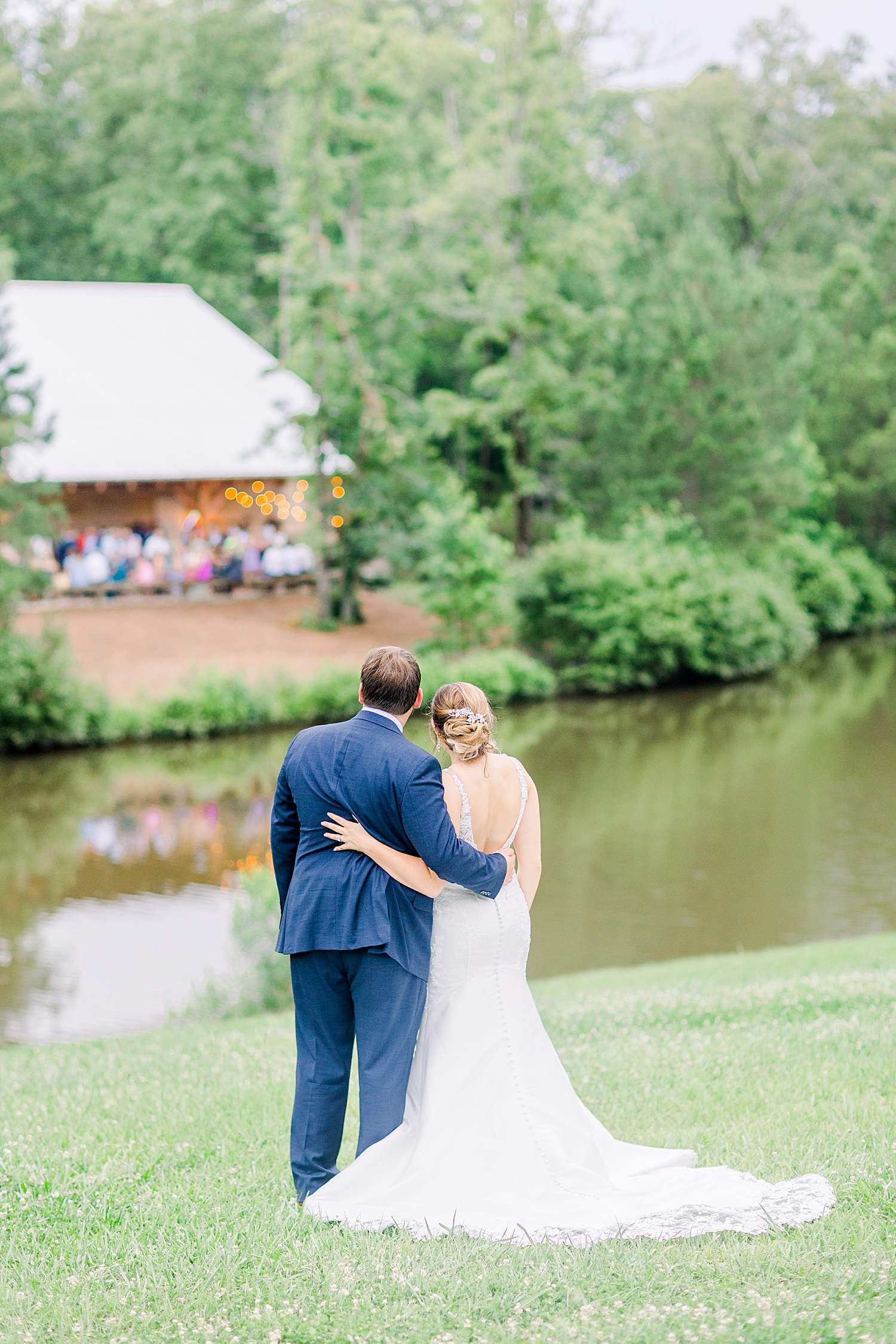 Newlyweds stand together by pond looking at wedding venue at Belle Farms in Sterrett Alabama