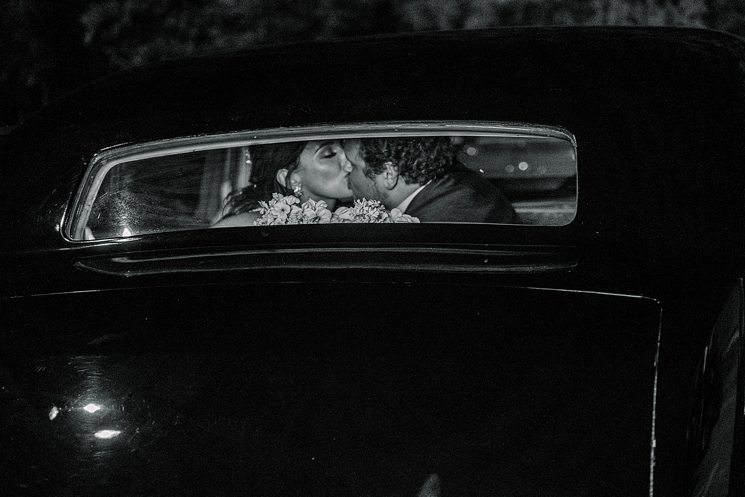 newlyweds kiss in the back window of a car as they drive away from Park Crest Events Wedding