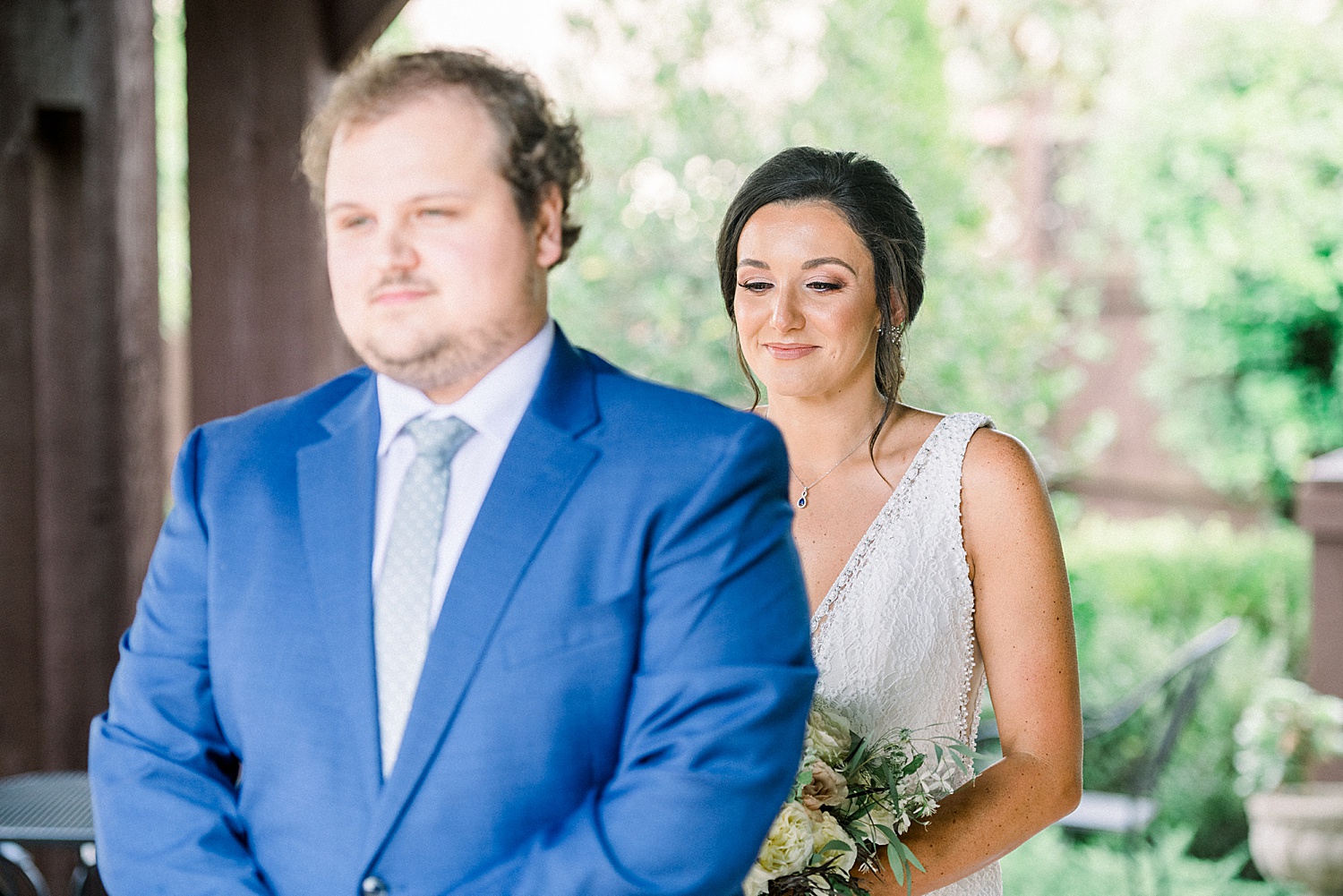 bride stands behind groom moments before first look