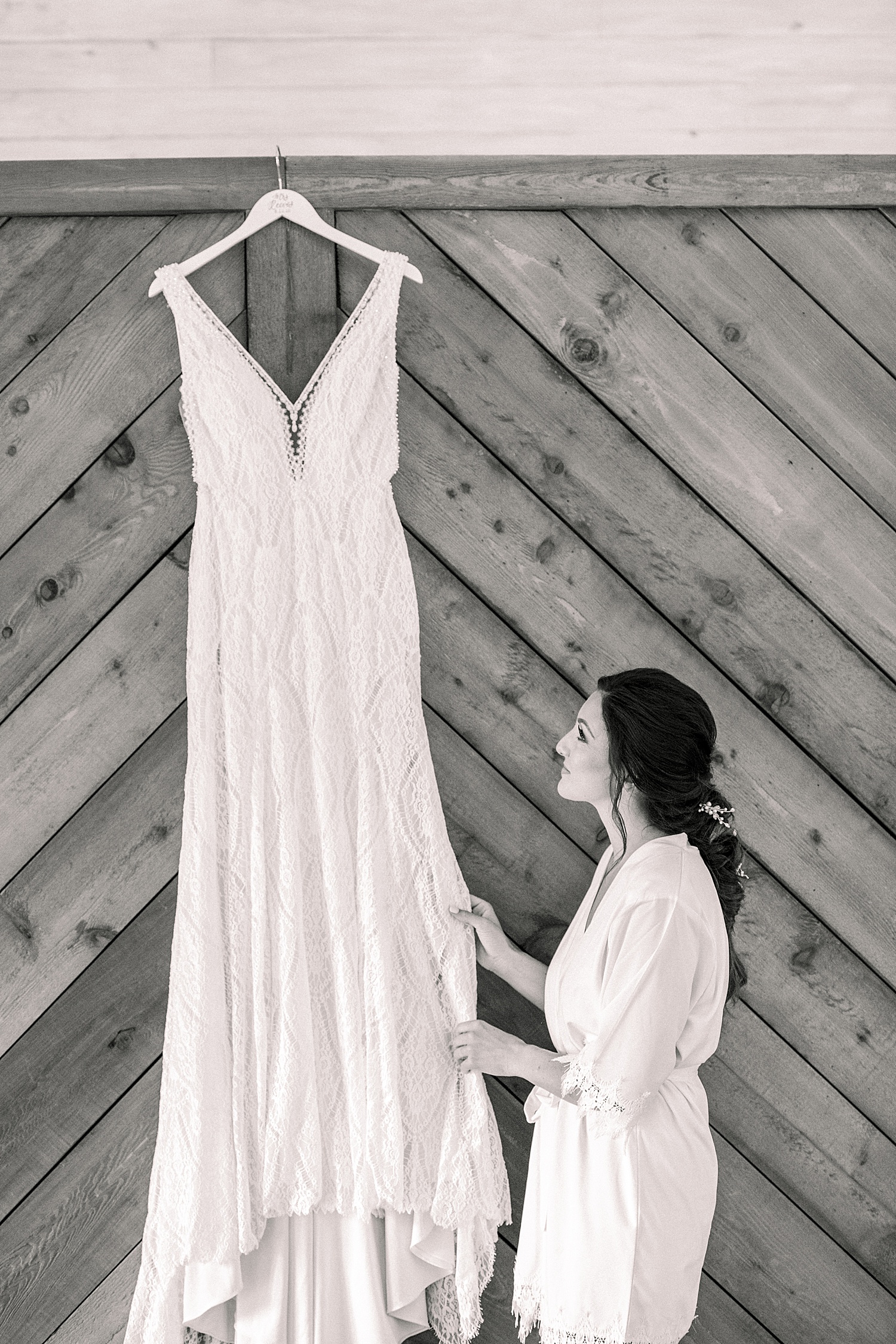 bride looking at her wedding dress hanging up