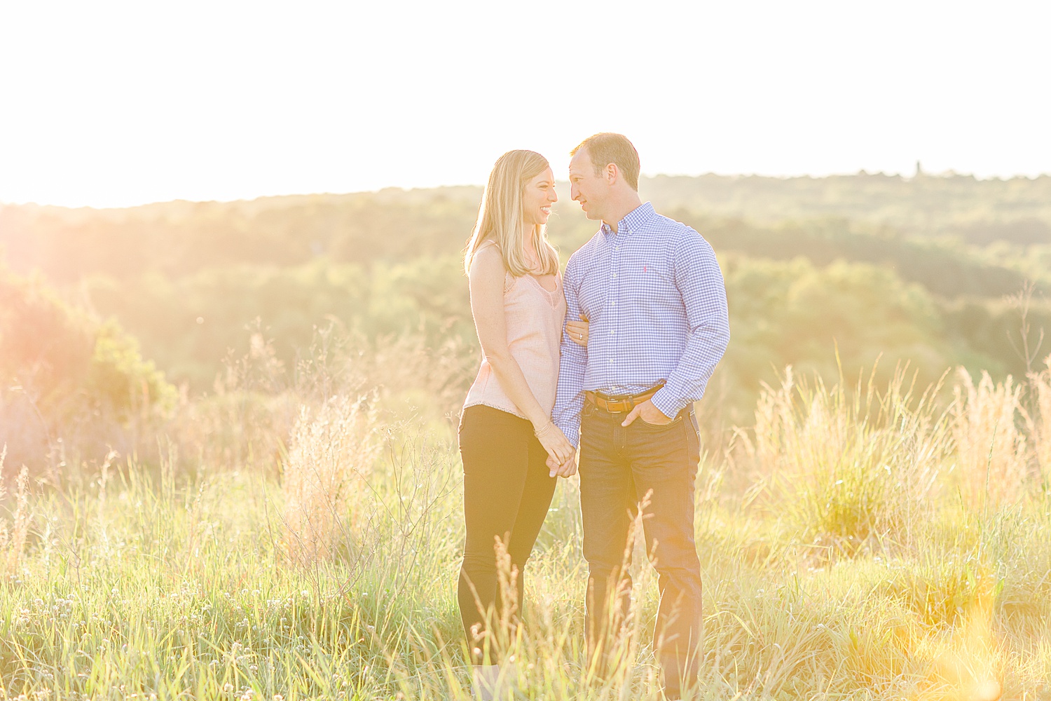 couple stand in open field in AL with sunlight glowing around them
