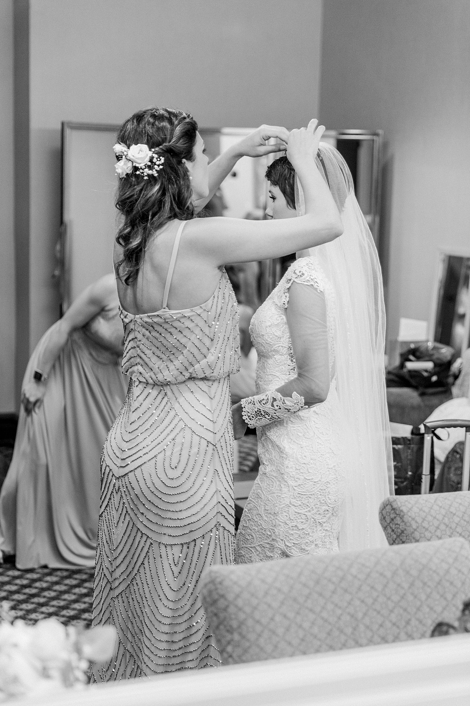 Bridesmaid helps bride with hair and veil