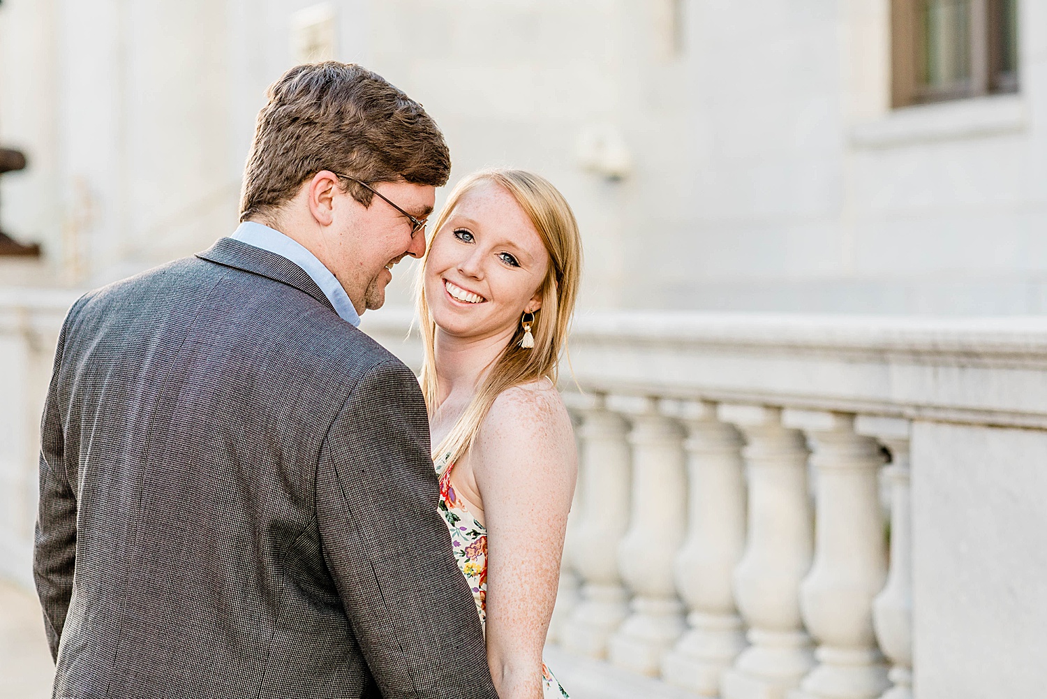 woman looks over mans shoulder during engagement session