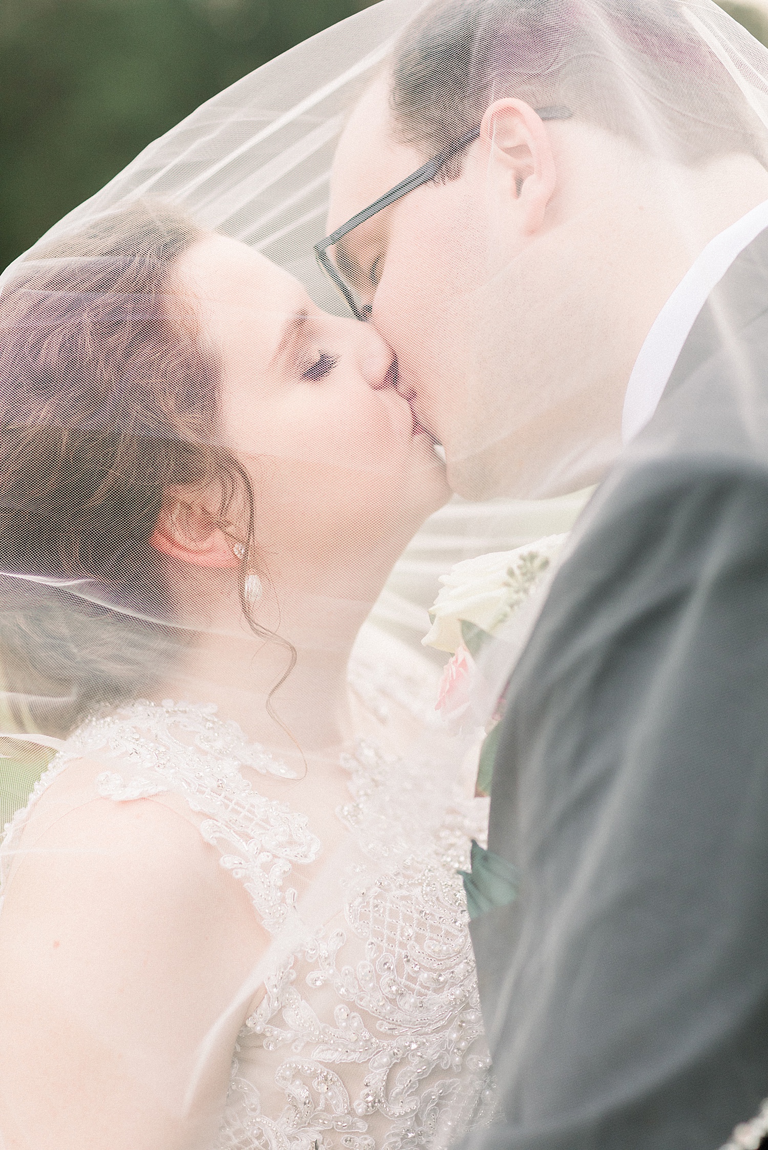 couple kisses under bride's veil during portraits
