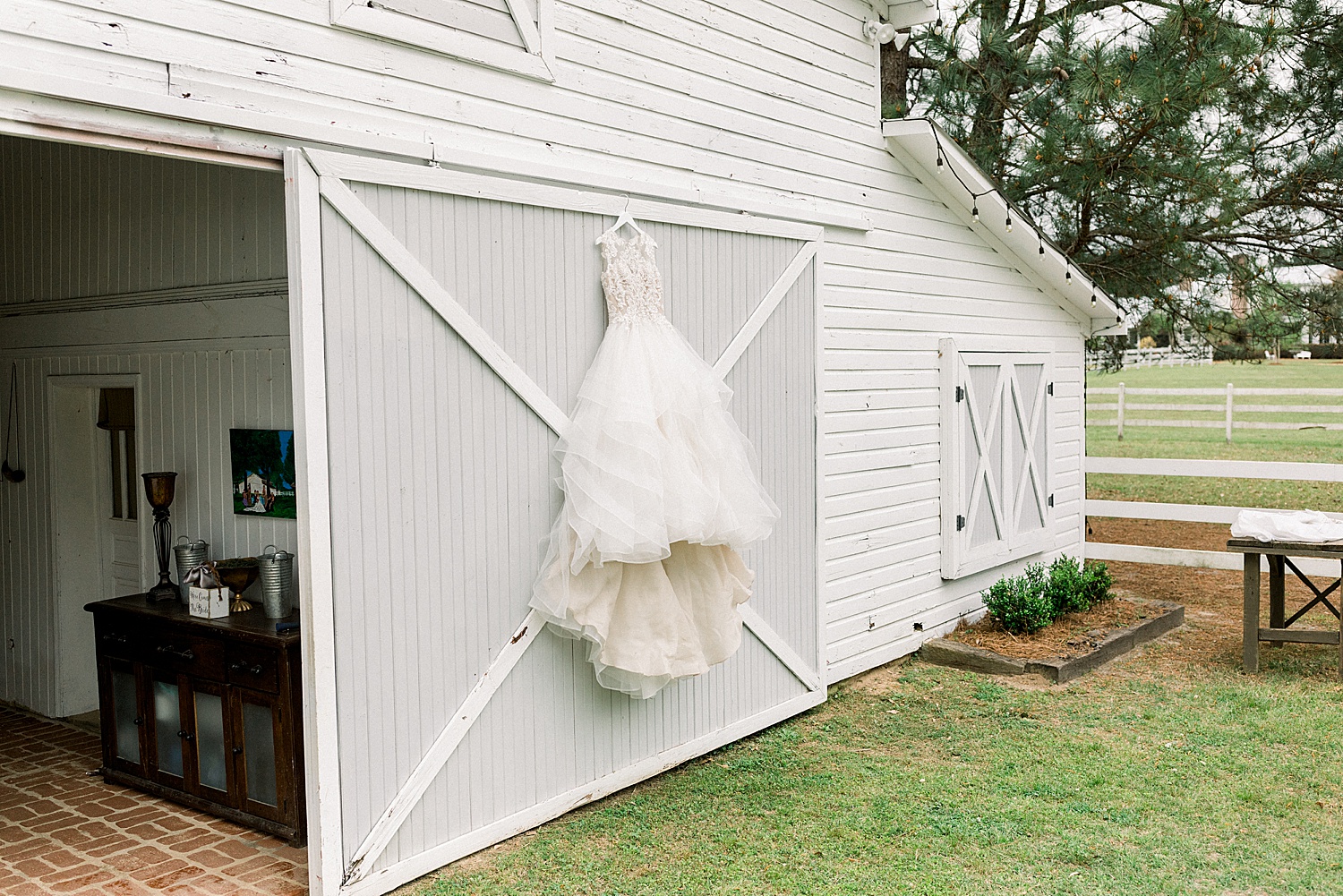 bride's wedding dress hanging on outside of barn door