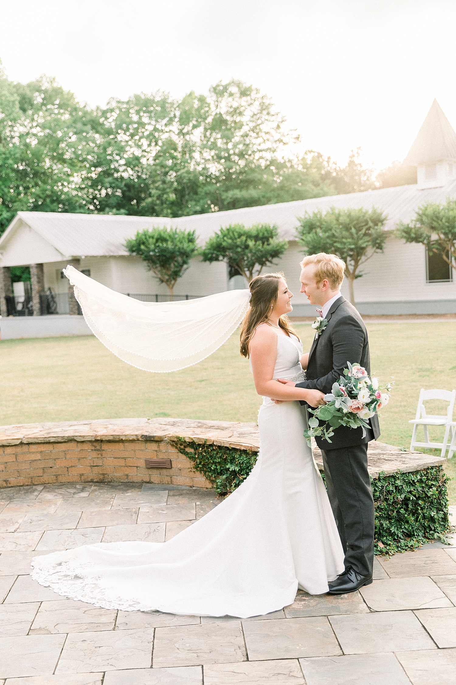 newlyweds in front of the Sonnet house in AL with brides veil floating in the wind