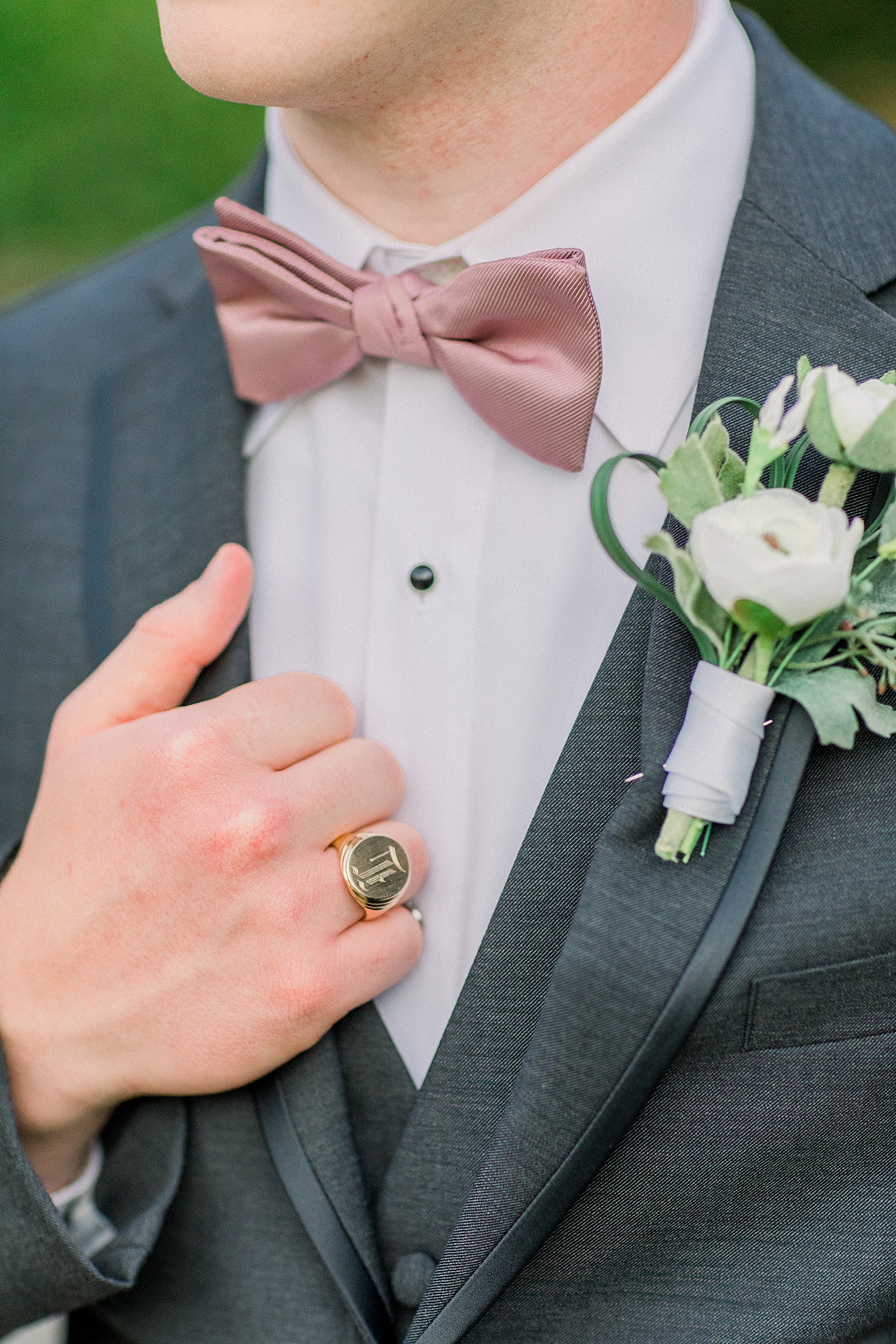 groom holding side of tux showing boutonniere