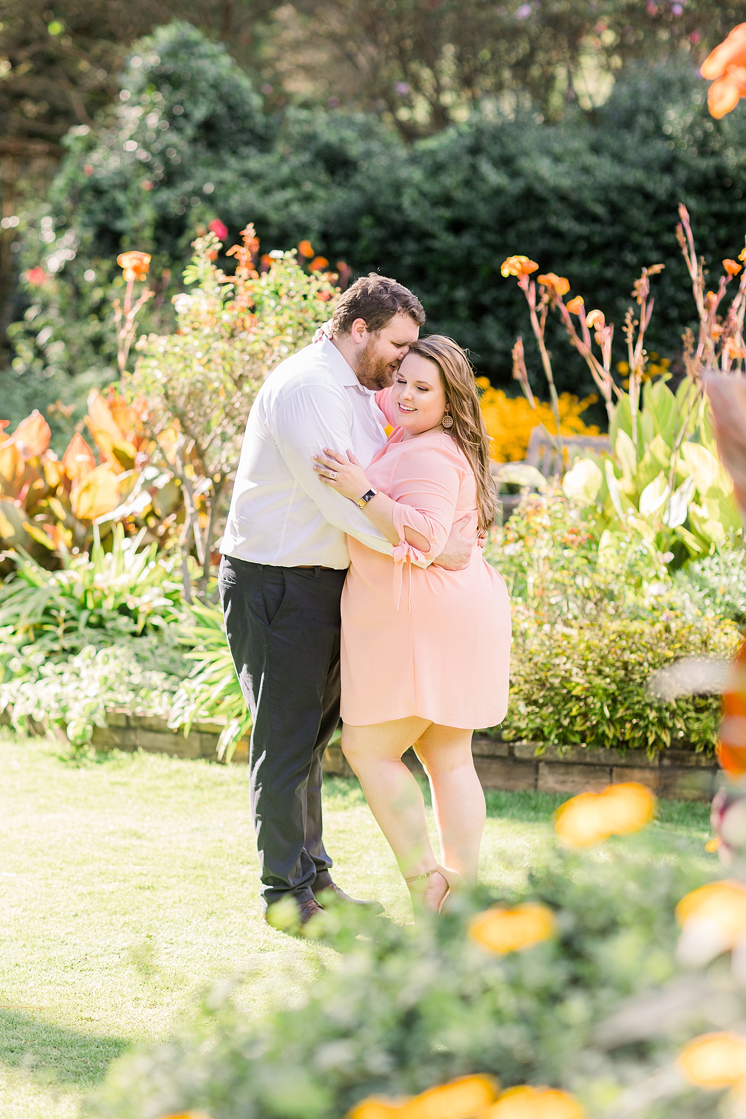 couple lean in together standing in garden of yellow flowers in Birmingham Alabama during engagement session